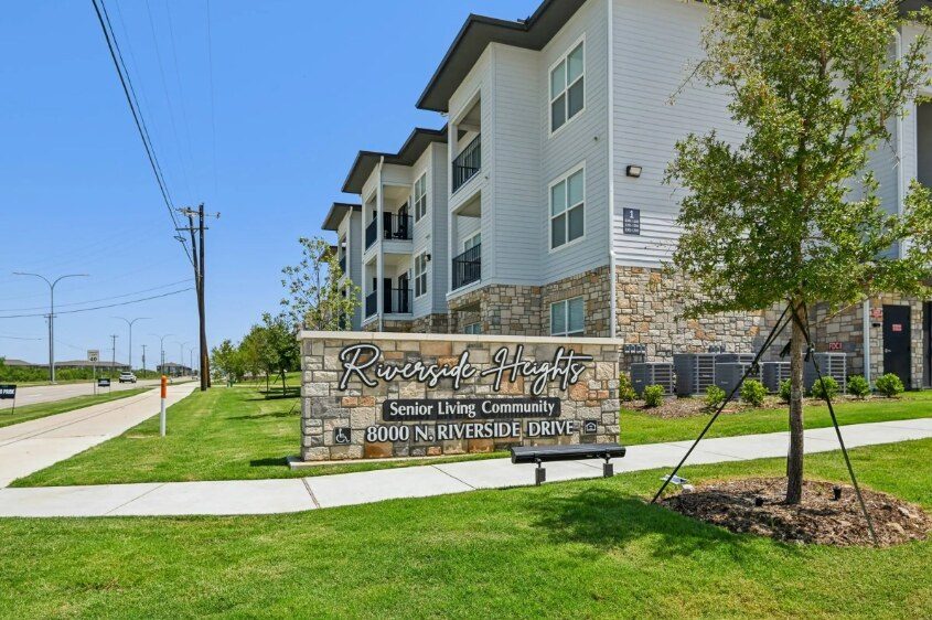 Riverside Heights senior living community in Fort Worth, Texas, showing the stone monument sign and three-story exterior